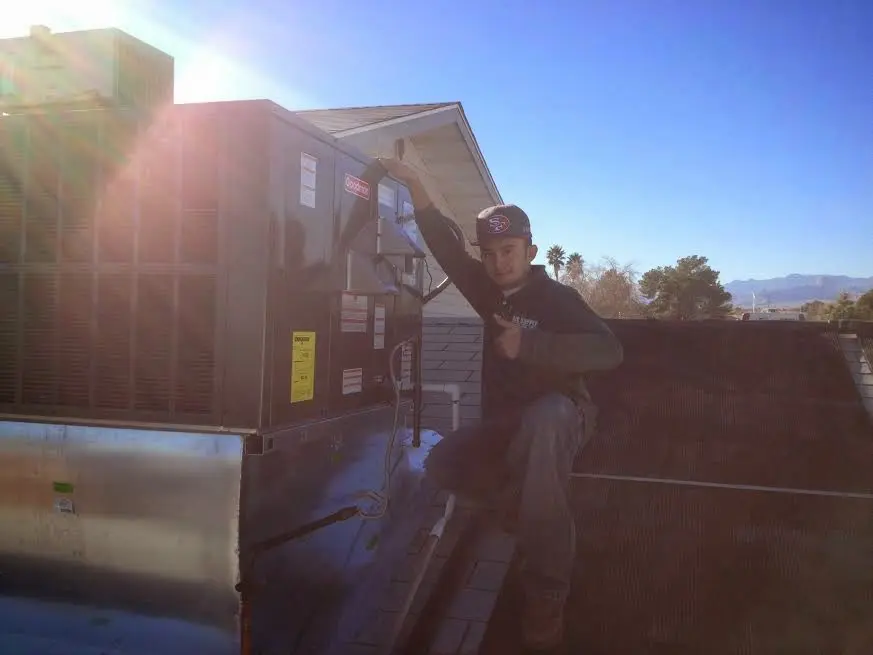 HVAC technician performing Heat Pump Repair on a rooftop unit in Four Corners